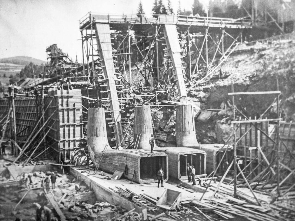 Historische Schwarz-Weiß-Aufnahme vom Bau des Kraftwerks Höllenstein mit Holzgerüsten und Betonröhren im Schwarzwald.
