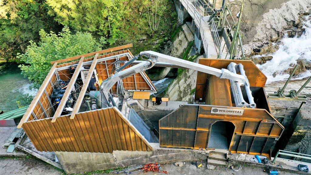 Wild metal Rechenreinigungsmaschine RRM am Kraftwerk Schattwald bei Wartungsarbeiten in bewaldeter Schlucht.