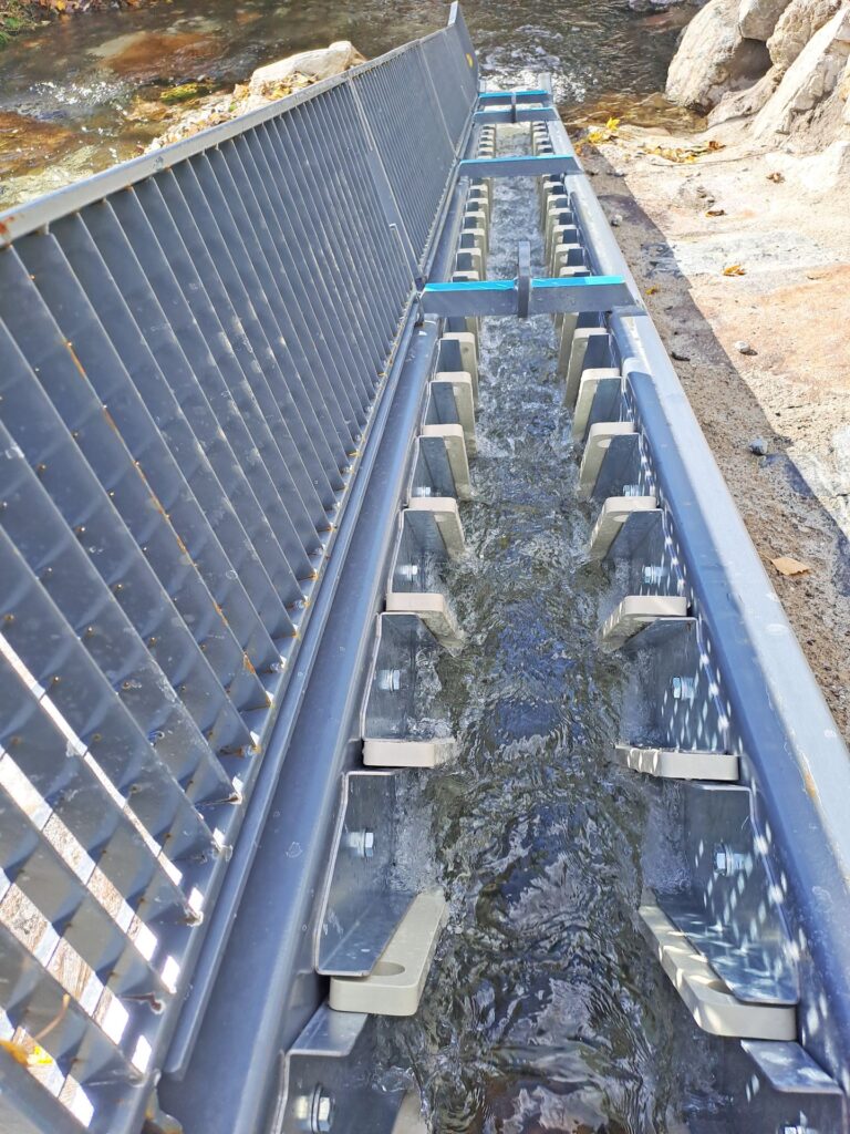Fischtreppe aus Metall mit strömendem Wasser in einem naturnahen Fließgewässer für ökologische Durchgängigkeit.