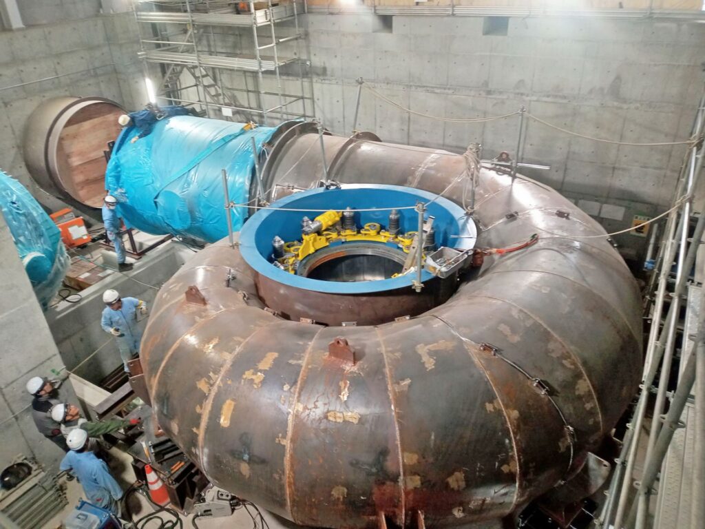 Arbeiter bei der Casing Installation einer massiven Wasserturbine in einer Industrieanlage aus Beton.