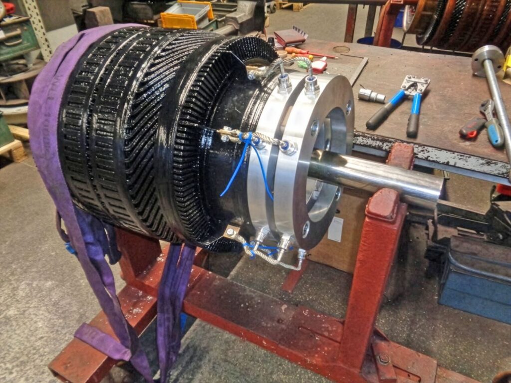 Großes schwarzes Industrie-Getriebe mit Metallflansch auf rotem Montagebock in einer Werkstatt.