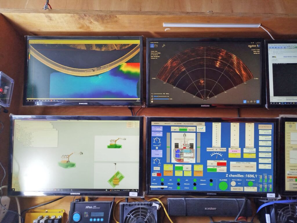 Überwachungsstation mit vier Monitoren, die Echolot-Scans, Radardaten und industrielle Steuerungssysteme anzeigen.