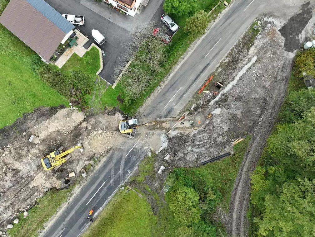 Luftaufnahme der Baustelle am KW Mühlbach mit zwei gelben Baggern bei Erdarbeiten an einer Landstraße.