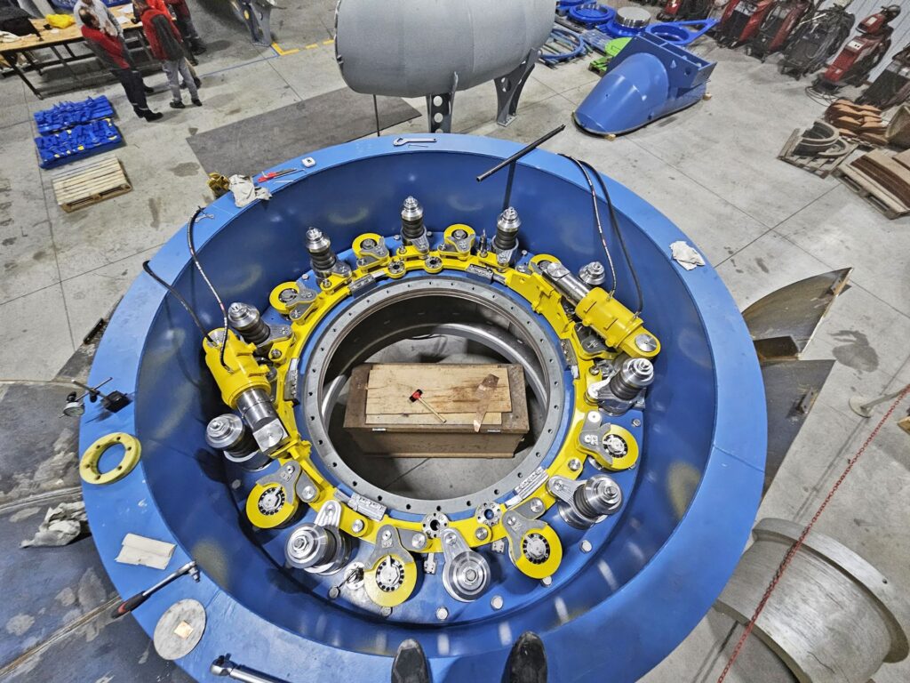 Blauer Leitapparat KW Uchiyama 200 x 150 mm mit gelben Mechanik-Komponenten in einer Werkstatthalle.