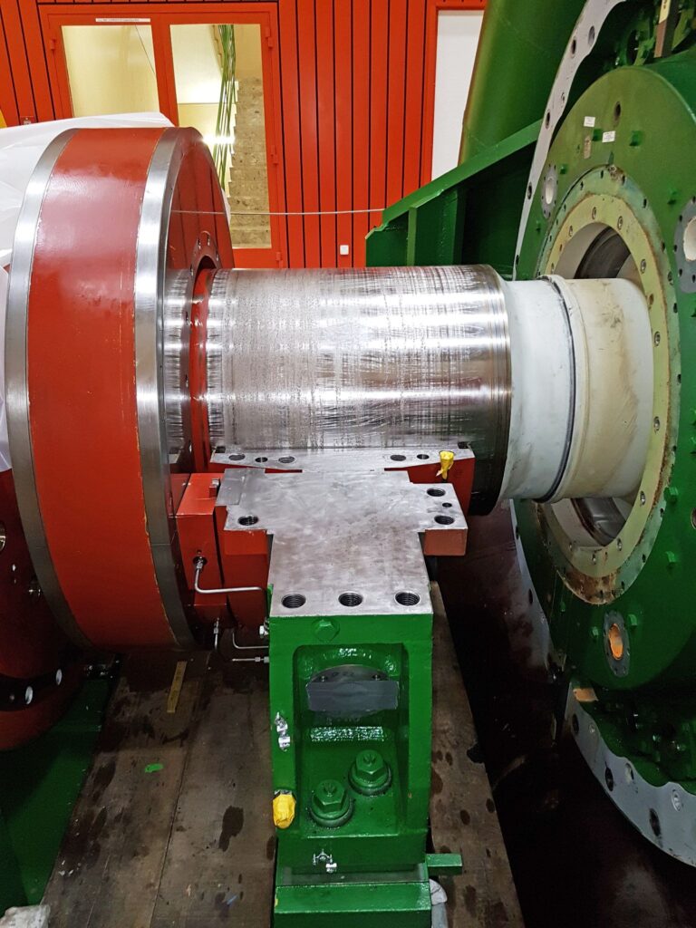 Massiver KWO-Maschinenschaden an einer zerkratzten Metallwelle zwischen grünen und roten Anlagenbauteilen.