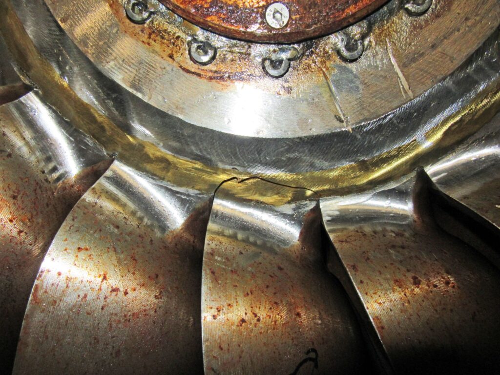 Nahaufnahme eines Risses an einer metallischen Kurbelwellen-Wange (KWO Schaden) mit Korrosionsspuren und Schweißnähten.