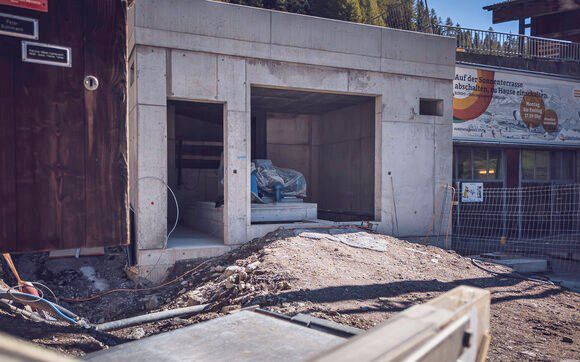 Modernes Krafthaus aus Sichtbeton im Rohbau mit freiliegender Turbine auf einer Baustelle in den Bergen.