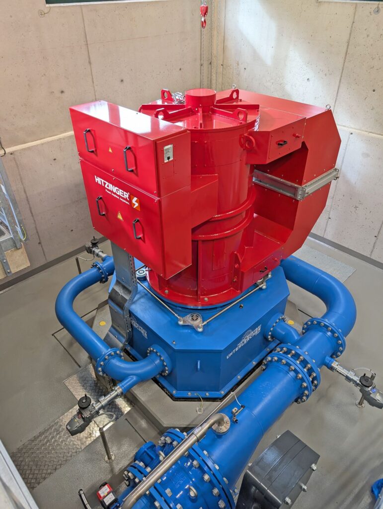 Roter Hitzinger Generator auf blauem Unterlercher Turbinengehäuse in einer Industrieanlage mit blauen Rohrleitungen.