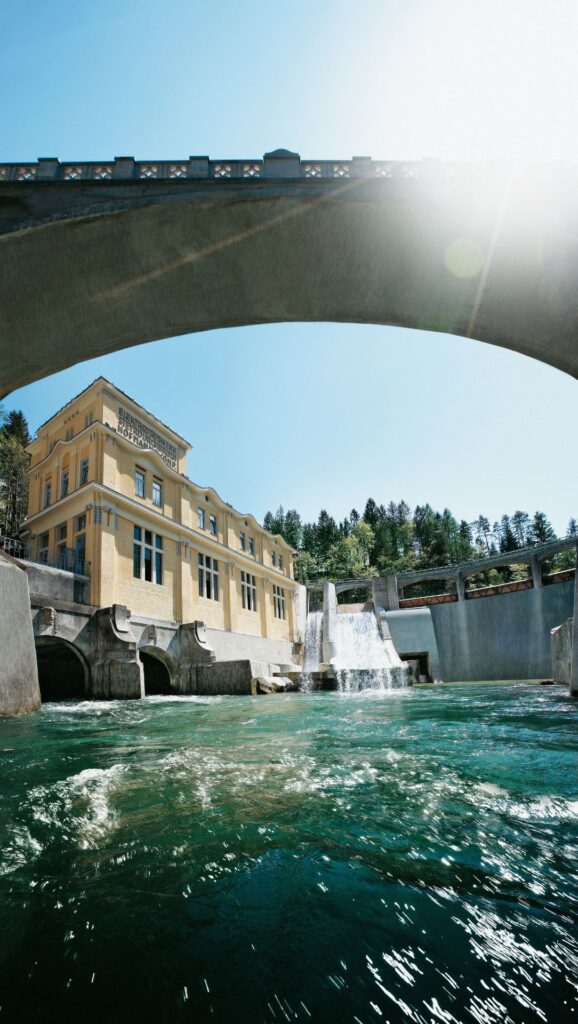 Wasserkraftwerk Steyrdurchbruch an der Steyr mit Jugendstil-Fassade, Wehranlage und Wasserfall unter einer Bogenbrücke.