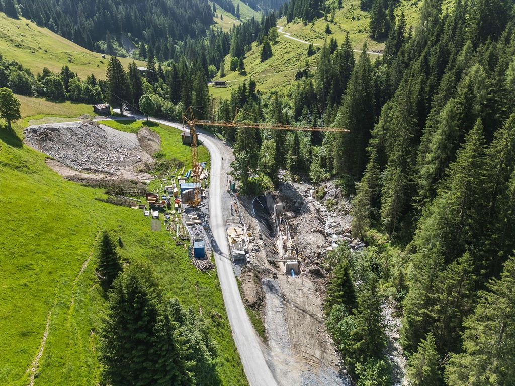Baustelle von Empl Bau im Mai 2025 mit gelbem Kran an einer Bergstraße im Wald, Luftaufnahme von Defrancesco.
