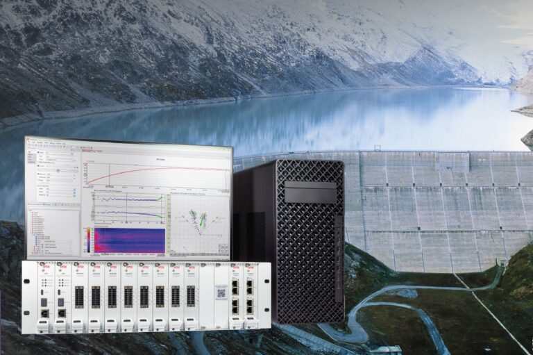 IFTA Messsystem mit Monitor, Server und Hardware-Modulen vor einer Wasserkraft-Staumauer in alpiner Umgebung.