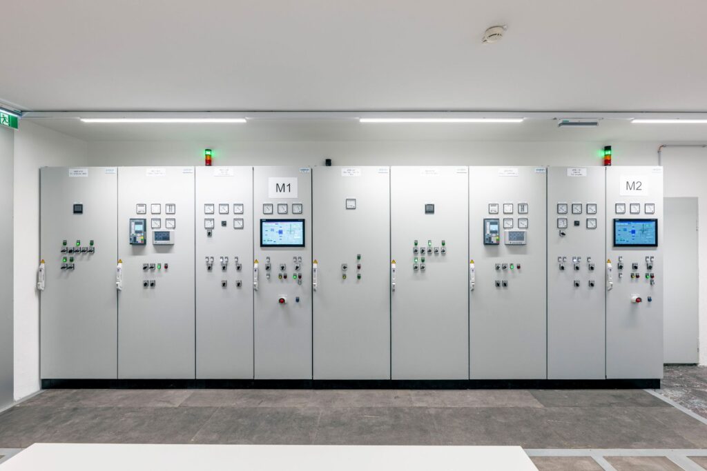 Großer Schaltschrank in einer Industrieanlage mit Displays, Schaltern und Steuerungstechnik für M1 und M2.