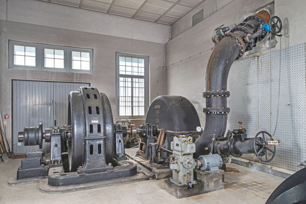 Historische Maschinensätze und Rohrleitungen im Kraftwerk Schattenhalb mit Vevey-Turbine und großem Generator.