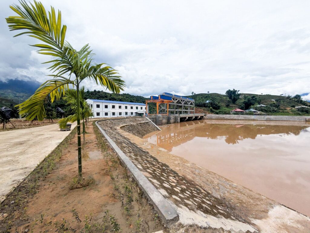 Wasserkraftwerk Na An von Gugler mit Staubecken, Industriegebäuden und Palmen vor grüner Hügellandschaft in Vietnam.