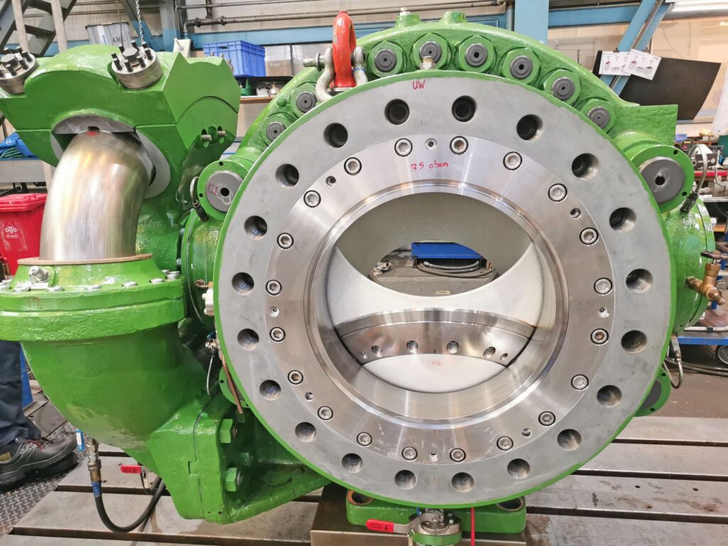Großer grüner Kugelhahn aus Stahl in einer Industrie-Werkstatt, massives Metallgehäuse mit Flansch und Verschraubungen.