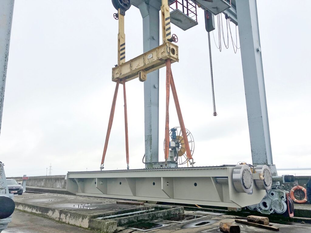Kran hebt massive Stahlkonstruktion am Wasserkraftwerk Kruonis; industrielle Verladearbeiten mit Schwerlastgurten.