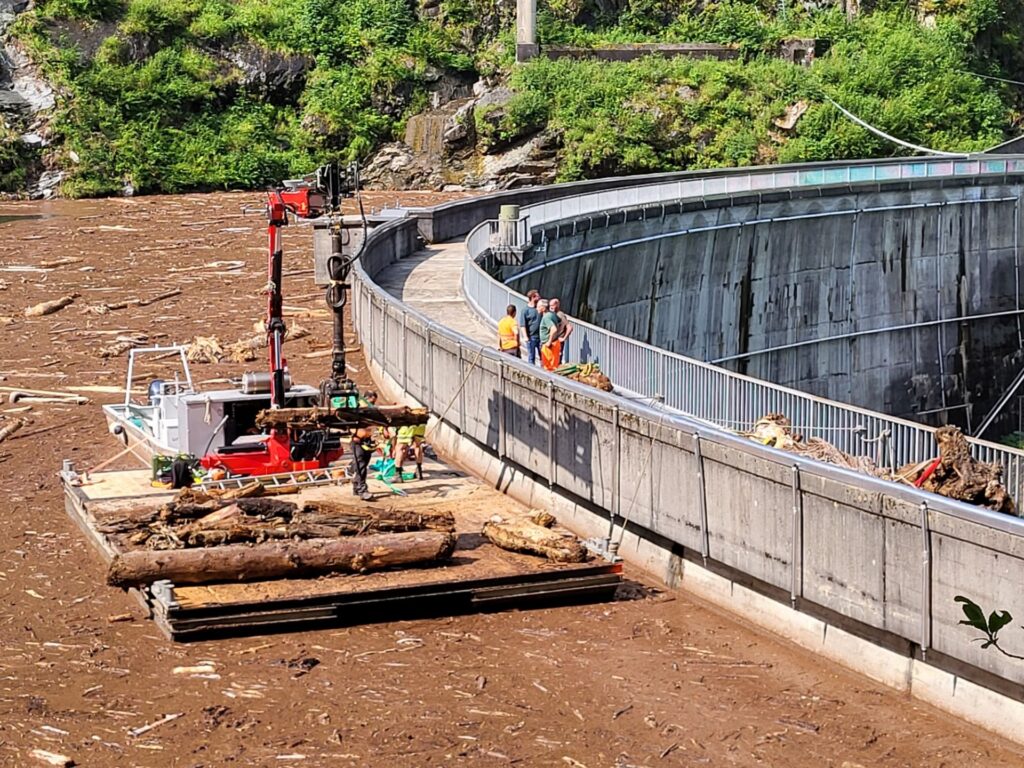 Schwimmbagger mit Kran bei der Entfernung von Schwemmholz an der Staumauer Roggiasca im Misox nach einem Unwetter.
